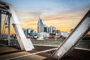 Nashville Tennessee skyline at sunset framed by steel beams of the John Seigenthaler Pedestrian Bridge